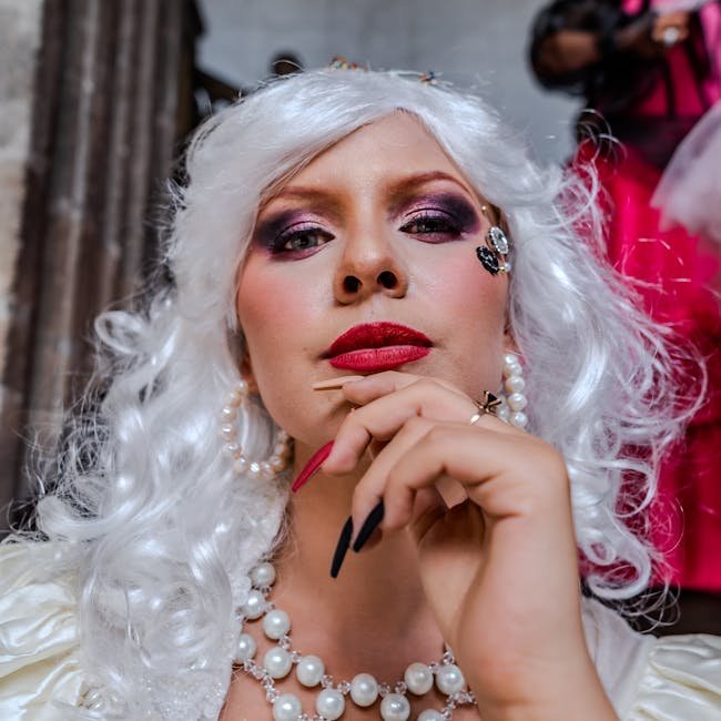 A glamorous woman with elaborate makeup and jewelry, exuding elegance and confidence indoors.